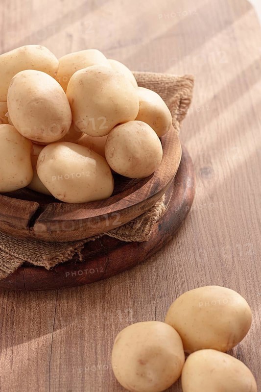 Boiled new potatoes, in a wooden bowl, on a rustic table, natural light, no people