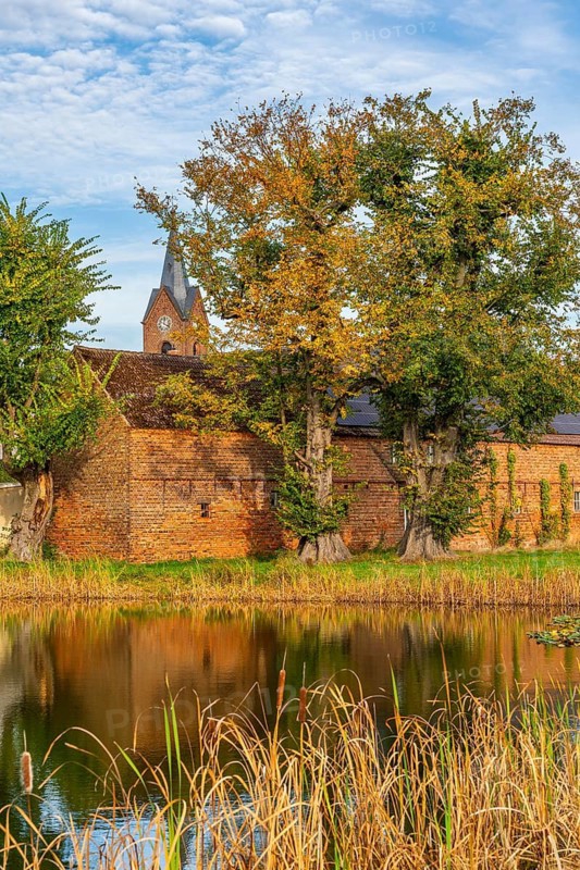 Village pond, farm and church in Oehna in autumn, Niedergörsdorf, Fläming, Brandenburg, Germany