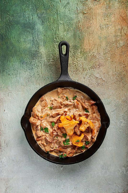 Fried chanterelle mushrooms, in cream sauce, in a cast-iron pan, homemade, no people