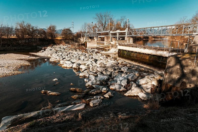 An old water weir surrounded by stones, sunny landscape and clear sky, Neunkirchen, Lower Austria, Austria