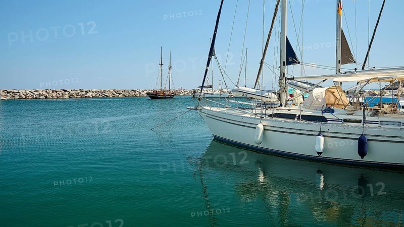 Sailing boats calmly moored in the harbour with clear blue water under a blue sky, Pali village, Pali, volcanic island, Nisyros, Dodecanese, Greek Islands, Greece