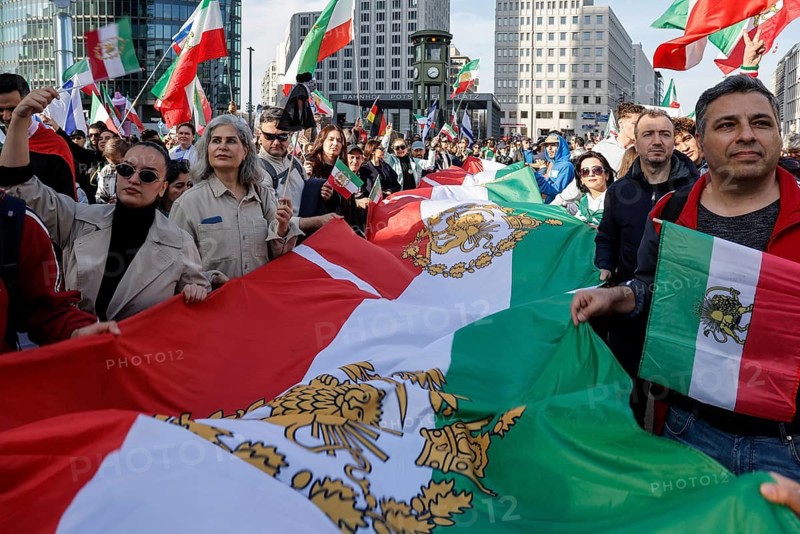 Iranians demonstrate with a large imperial Iranian flag on the day of the US and Israeli attack on Iran in Berlin, 28.02.2026. People cheer the rumor that Obermullah Khamenei died in the attack, Berlin, Berlin, Germany