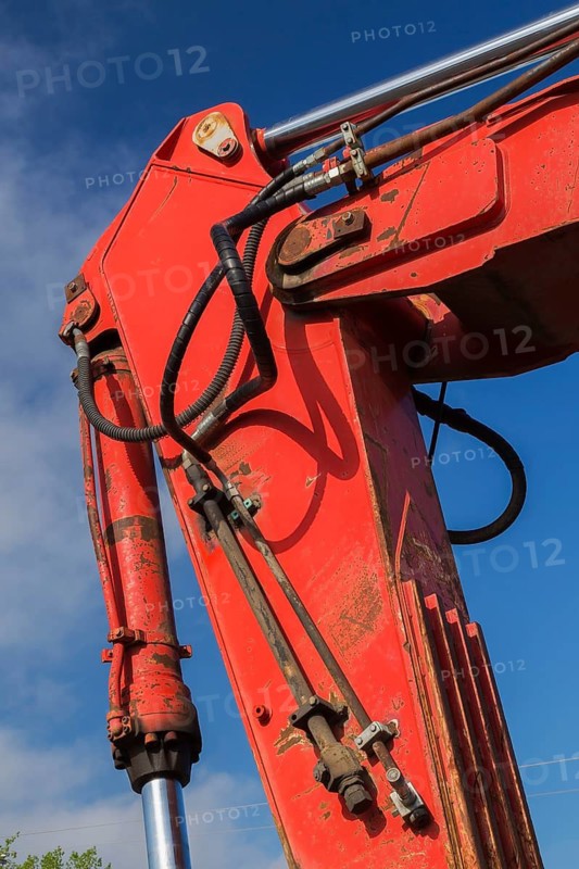 Electrical power and hydraulic fluid supply lines on hinged boom of red painted backhoe excavator, Quebec, Canada