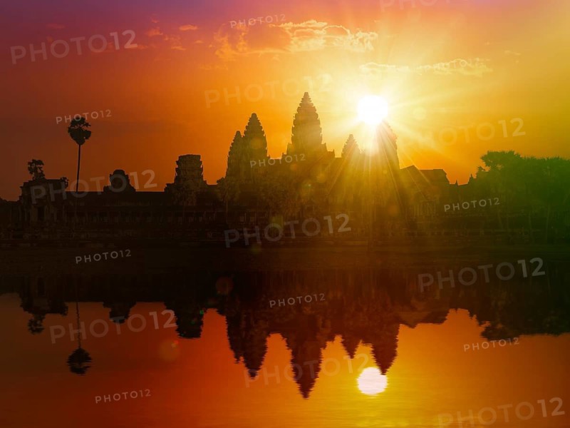 Cambodia landmark Angkor Wat silhouette with reflection in water on sunset. With lens flare and light leak