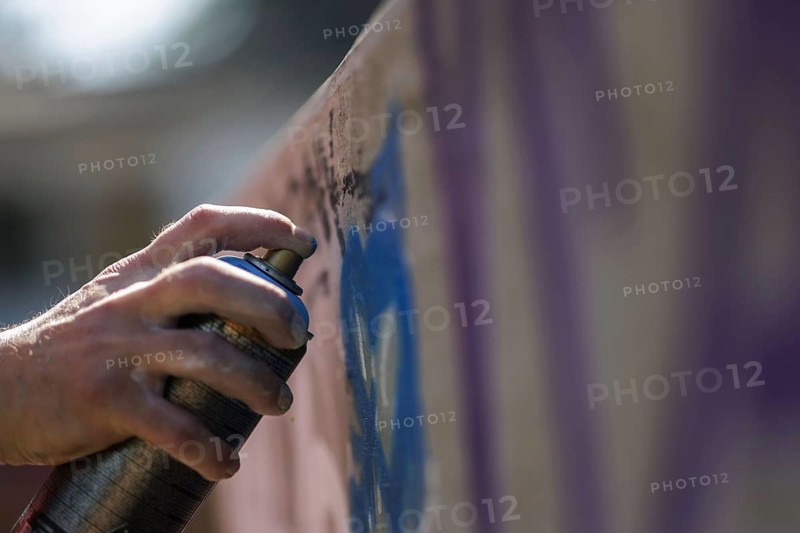 A man sprays graffiti on a wall with a spray can. Berlin, 14.08.2024