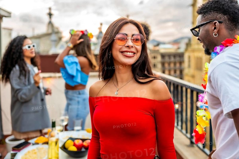 Chic beauty woman smiling while friends partying outdoors in a rooftop in the background