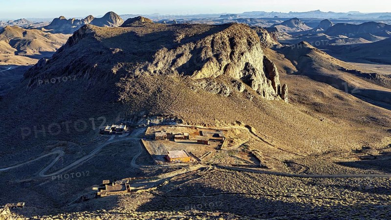 Small settlement at the foot of a large rock in a dry, barren region, The landscape of the Ahaggar Mountains in the Sahara in Algeria