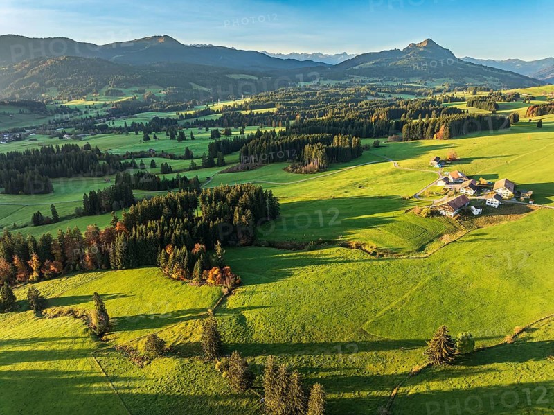 Mountain range near village Wertach, view to mt. Gruenten, sunrise, fog in valley, traditional farm, aerial view, Allgaeu, Bavaria, Germany