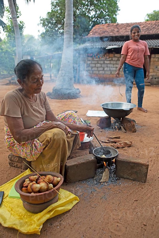 Local people, Sri Lankan woman, 63 years old, frying traditional doughnuts on a fire on the ground, Sella Kataragama, Kataragama, Uva Province, Sri Lanka