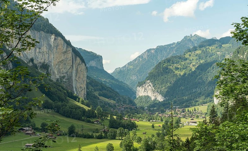 Lush green surroundings encapsulate the serene village nestled in the Lauterbrunnen valley, highlighted by majestic cliffs and alpine peaks