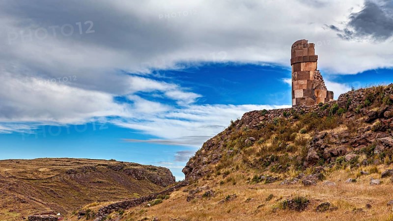 Historic stone ruin on a hill against a blue, cloudy sky, The Chullpas of Sillustani near Puno in Peru