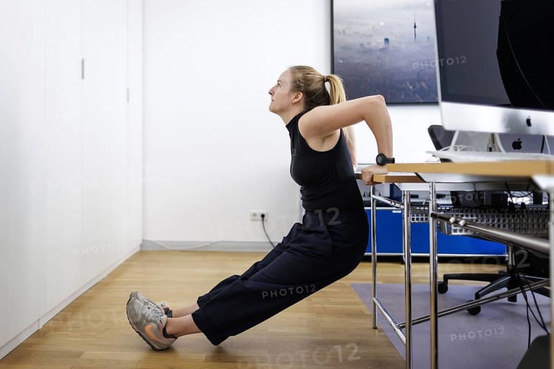 A woman does sports exercises at her workplace in an office in Berlin, 08/08/2024