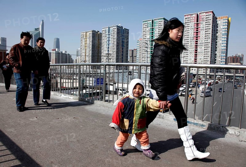 Beijing, CHN, 20.02.09 - A young Chinese mother holds her child's hand as she walks across a footbridge on a busy street in Beijing, CHINA