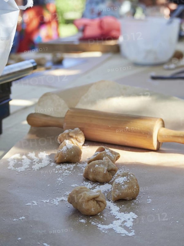 Making homemade stuffed whole wheat pasta, ravioli. Outdoor on a table with a wooden rolling pin