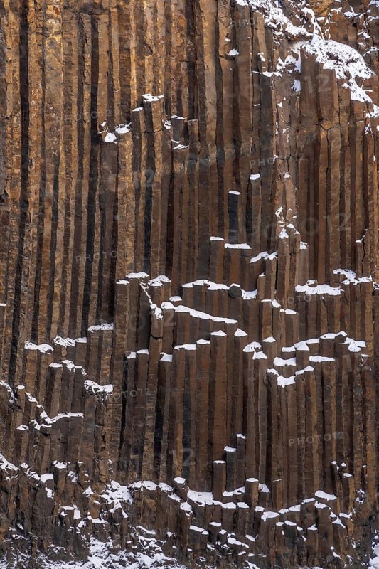 Hengifoss waterfall frozen in the cold Icelandic winter, detail of the volcanic cliffs