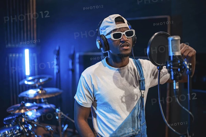 Young, stylish male singer captivating audiences while performing his latest hit in a professional music recording studio filled with creativity