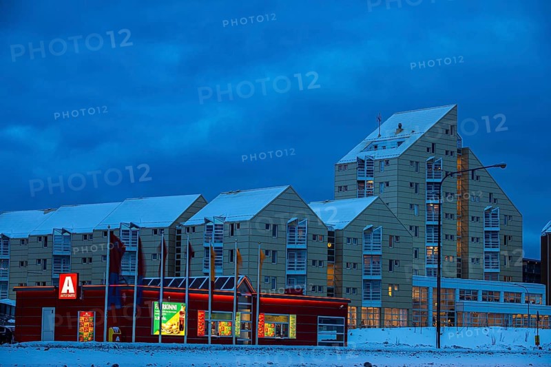 Illuminated supermarket at dawn, behind it apartment buildings in modern architecture, Reykjavik, Reykjanes Peninsula, Sudurnes, Iceland