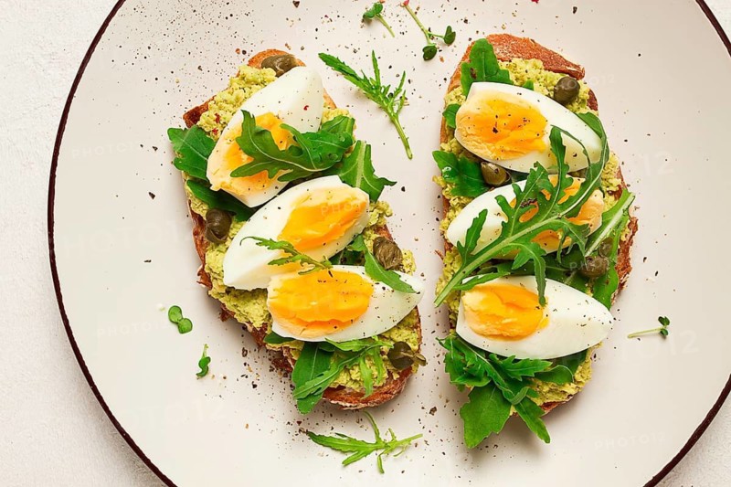 Sandwich with mashed avocado, boiled egg, and arugula, on bread, homemade, breakfast