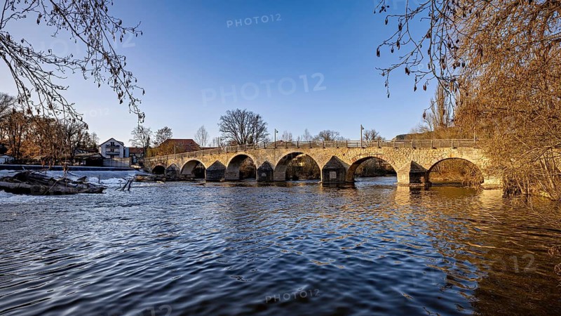 Stone bridge over a river in daylight surrounded by winter nature, The Burgau Bridge in the Saale Valley near Jena in Thuringia