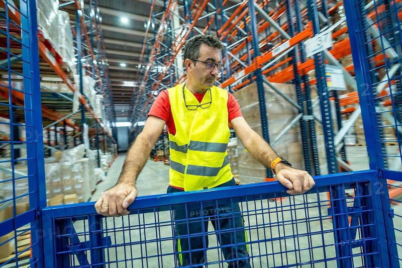 Three quarter length photo of a mature man in protective gear working in a storage warehouse