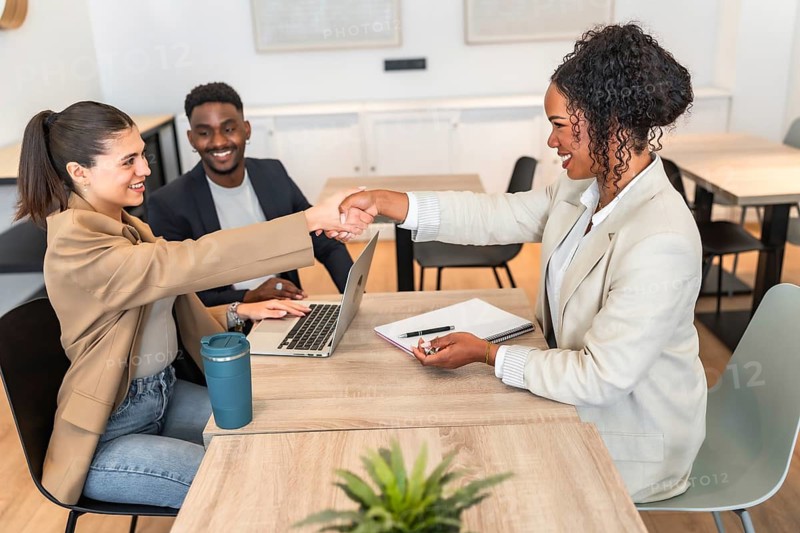 Businesswomen shaking hands after reaching an agreement during a meeting in a modern office, celebrating their collaboration