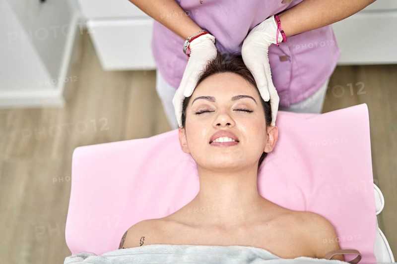 A skilled practitioner provides a soothing head massage to a client in a beauty salon. The serene environment emphasizes relaxation, enhancing the overall aesthetic experience