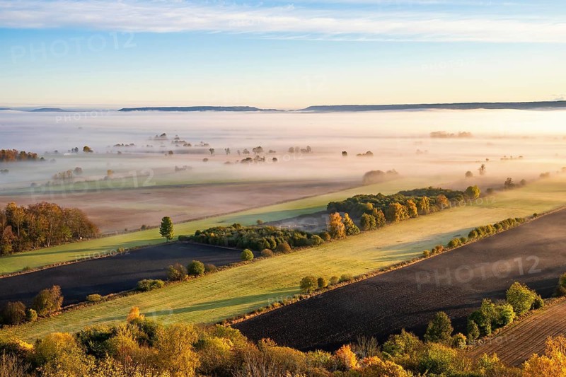 Scenics view of a beautiful rural landscape with fields and low morning fog at sunrise in autumn