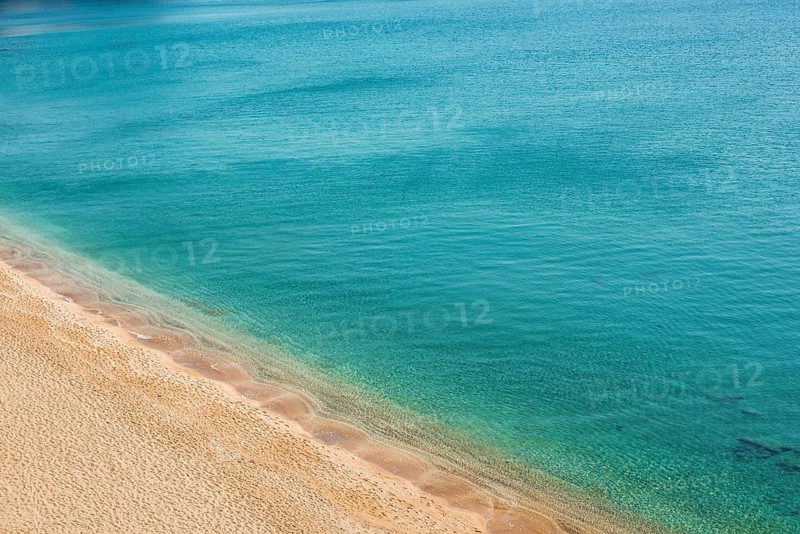 A tranquil view of Paleochori Beach on Milos Island, Greece, showcasing golden sand meeting crystal-clear turquoise waters under a clear sky, perfect for a peaceful escape