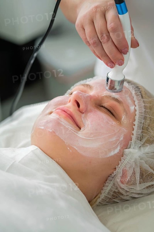 A client enjoys a rejuvenating RF lifting procedure with a specialist applying conductive gel and a metallic device on her skin