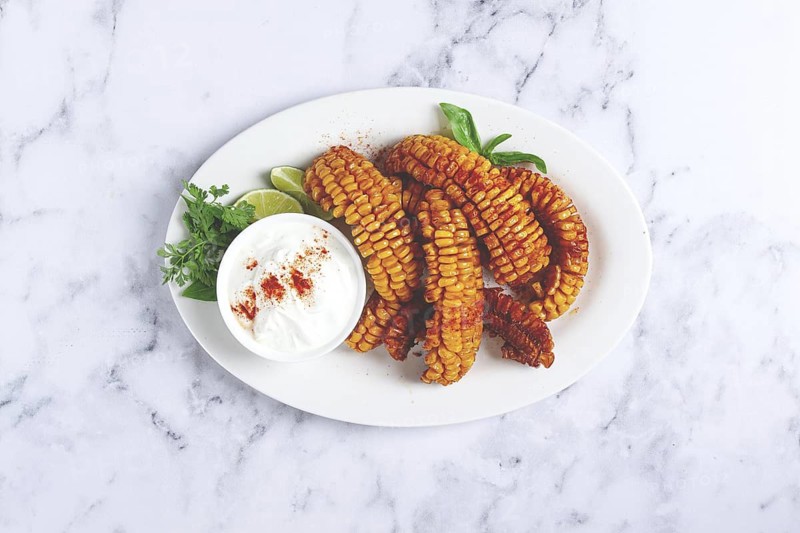 Corn ribs, with cream sauce, spices and lime, appetizer, on a white plate, homemade, no people
