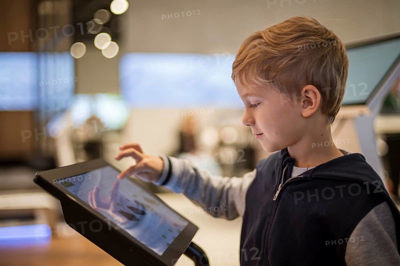 Young boy chooses shopping on the monitor screen in a modern store