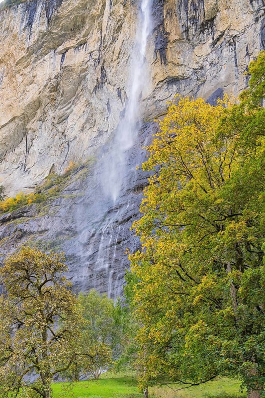 Waterfall on high rocks with colourful autumn trees in the surroundings, Lauterbrunnen, Switzerland