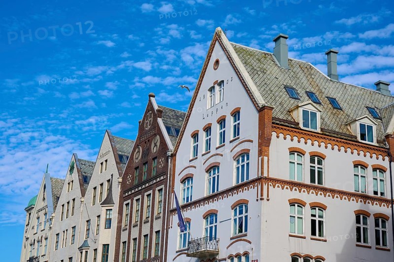 Row of historic Hanseatic houses with striking facades under a clear blue sky, Bryggen, Bergen, Vestland, Norway