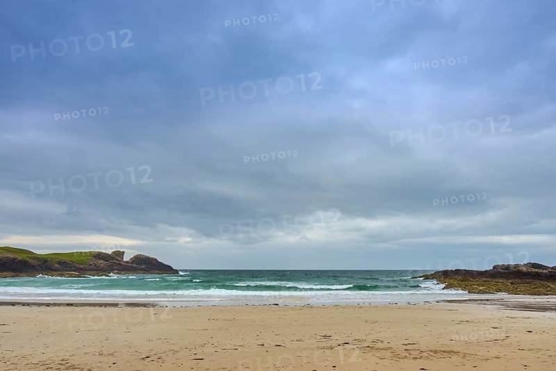 An empty sandy beach overlooking the vast sea under evenly covered skies, Clachtoll Beach, Clachtoll, Lairg, Scotland, United Kingdom, Great Britain
