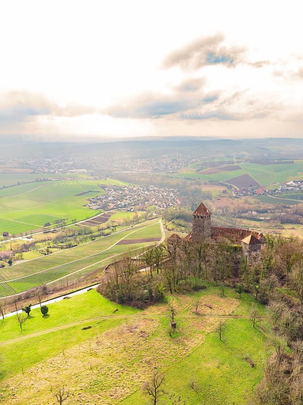 An old castle in the middle of a green landscape with a wide view of a village and fields under a cloudy sky, Lichtenberg Castle, Oberstenfeld, Germany