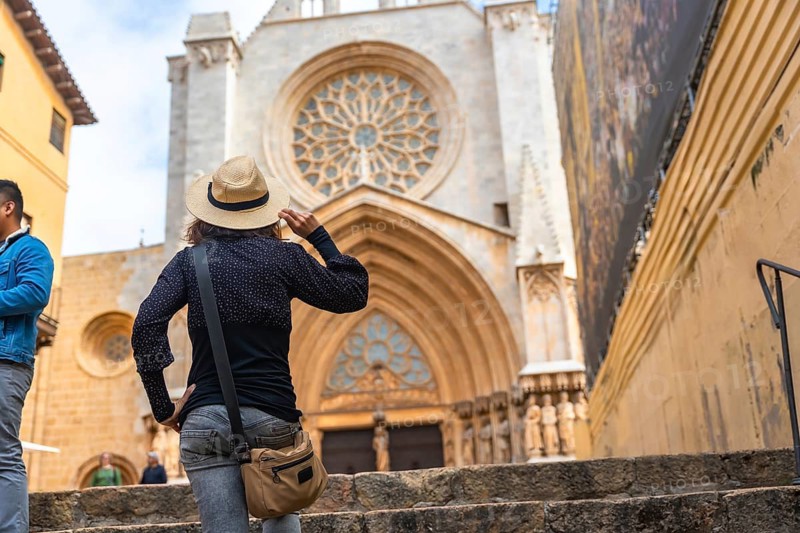 Tourist holding her straw hat while visiting the metropolitan cathedral basilica of tarragona, a roman catholic church in tarragona, catalonia, spain