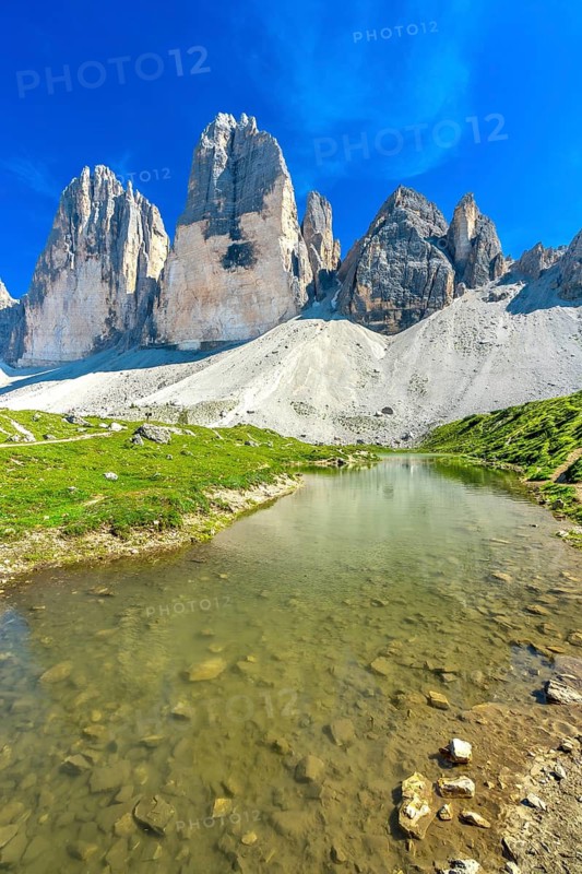 Crystal clear alpine lake reflecting the majestic tre cime di lavaredo peaks on a sunny summer day in the italian dolomites