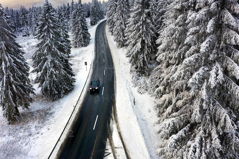 Aerial view, road leads through a snow-covered forest area near Sankt Andreasberg, 14 December 2019