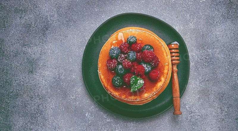 Breakfast, pancakes with berries and honey, top view, homemade, no people