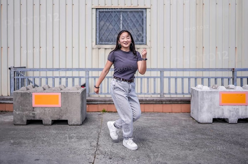 Happy millennial asian girl dancing free style in an urban space outdoors
