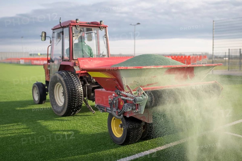 Pouring infill granules in to a football pitch with artificial grass in Lubin, Poland