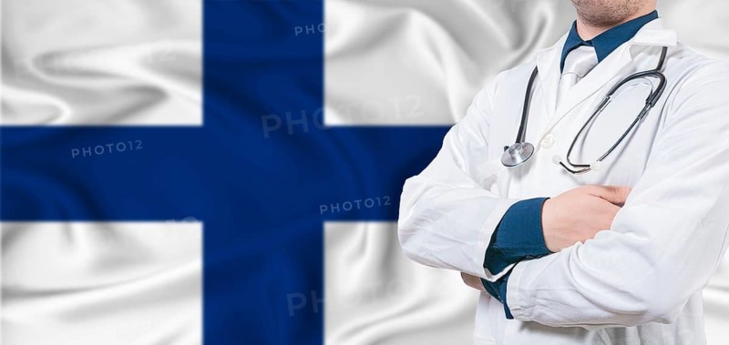 Finland Health Care concept. Male doctor on Finland flag. Doctor with crossed arms on Finland flag