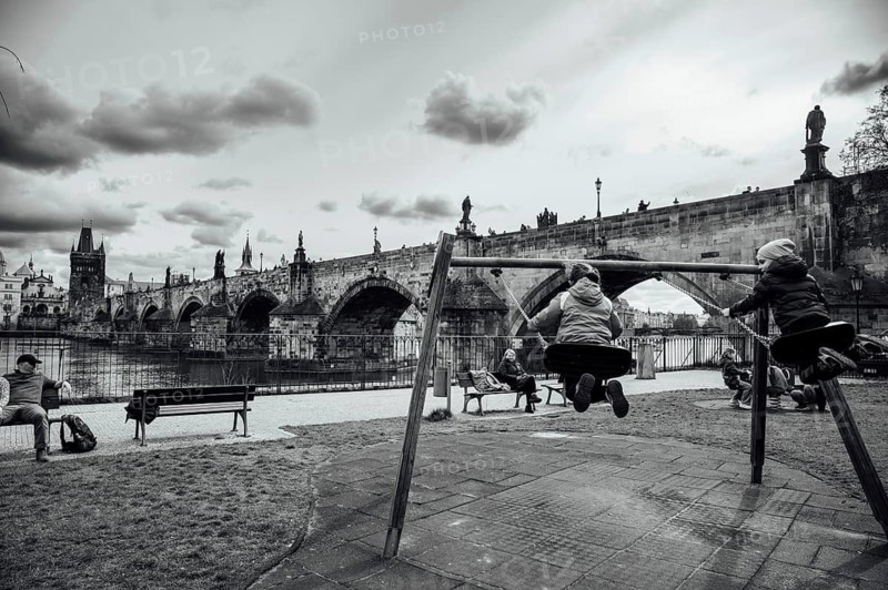 PRAGUE, CZECHIA - MARCH 25, 2023: Charles Bridge and children swinging in the foreground.