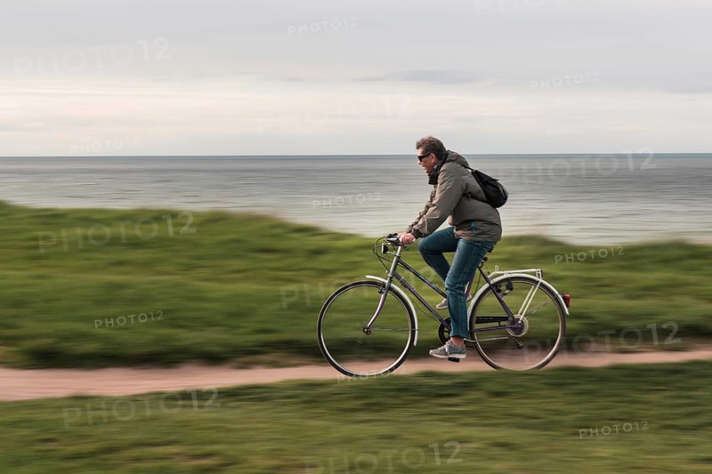 TRZESACZ, POLAND - MAY 1, 2018: The man riding a bike on the cliff above the sea