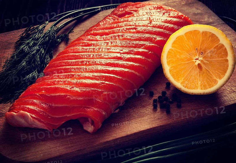 Vintage retro effect filtered hipster style image of fresh salmon piece on wooden cooking board with vegetables