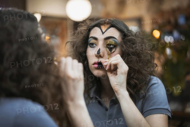 Hair and makeup preparations for the Halloween party, woman putting on her eyelashes with a tool