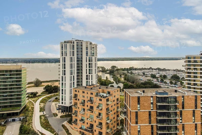 Contemporary residential buildings set against a serene waterfront landscape, showcasing innovative architectural designs and lush greenery
