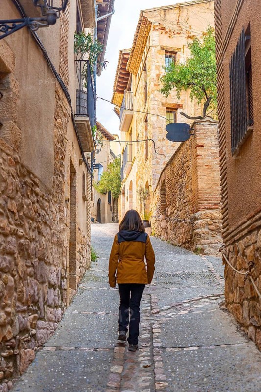 A tourist walking through the streets of the Pyrenean village of Alquezar, medieval town of Huesca, Spain