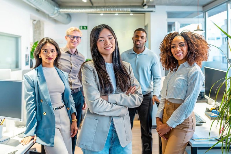 Diverse group of professionals posing together in a bright, modern coworking space, showcasing teamwork and collaboration