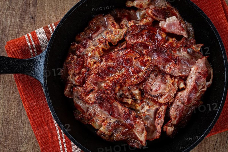 Crispy bacon, on a cast-iron skillet, on a wooden table, rustic style, no people